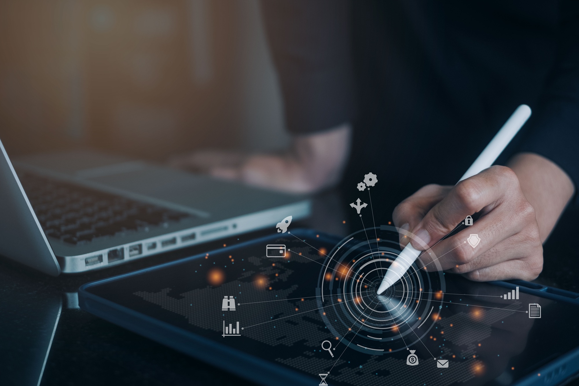 Person arbeitet mit Stylus auf einem digitalen Tablet neben einem Laptop – Symbol für individuelle Softwareentwicklung und digitale Anwendungen