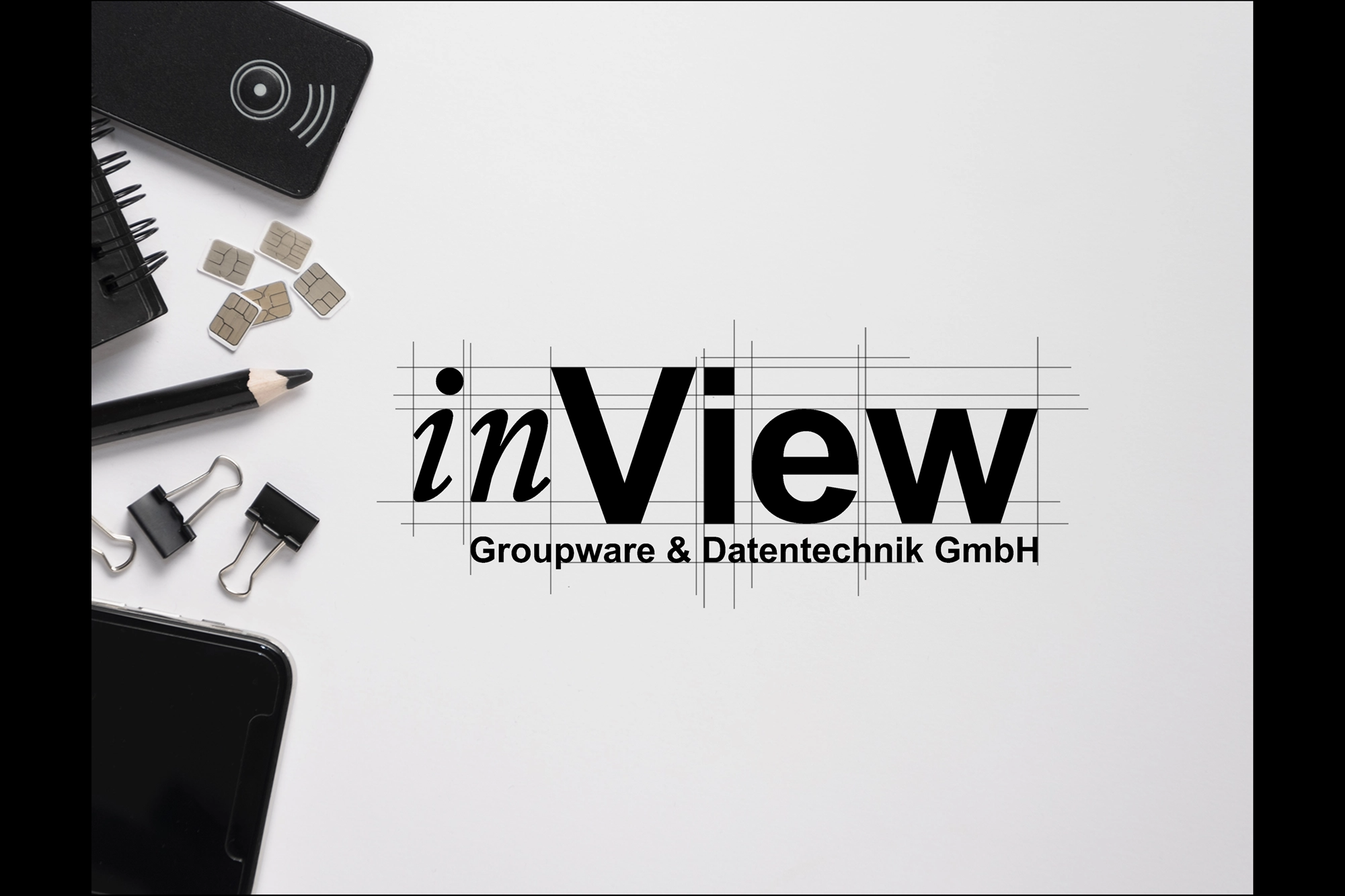 Weißer Arbeitsbereich mit Handy, Bleistift, Binderklammern und SIM-Karten auf der linken Seite; auffälliges schwarzes „inView“-Logo mit Gitterlinien und der kleinen Unterschrift „Groupware & Datentechnik GmbH“ mittig rechts, passend zur ganzheitlichen IT-Betreuung und modernen Kollaborationslösungen eines IT-Dienstleisters aus Freiburg